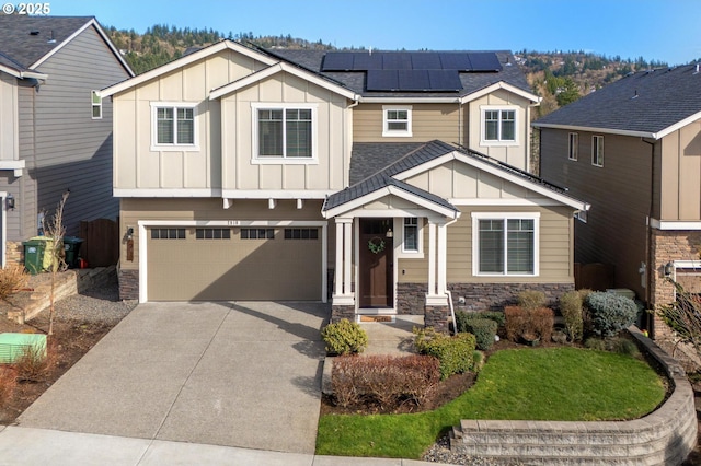 craftsman-style house with driveway, stone siding, and board and batten siding