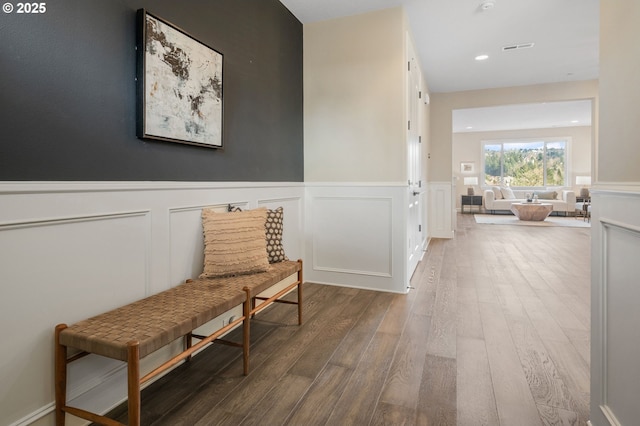 hall with visible vents, wood finished floors, and wainscoting