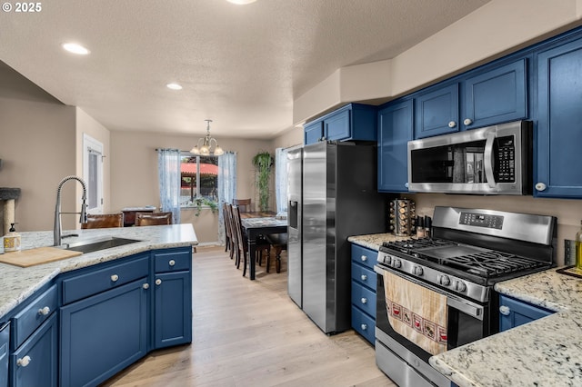 719 NE Quince Ave, Redmond, OR 97756 - kitchen with stainless steel appliances, blue cabinets, a chandelier, a textured ceiling, and recessed lighting