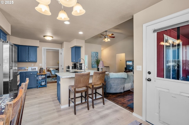 719 NE Quince Ave, Redmond, OR 97756 - kitchen featuring blue cabinetry, a peninsula, a breakfast bar, light wood finished floors, and lofted ceiling