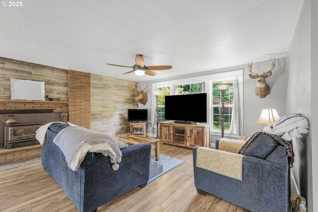 2472 Willamina Ave, Forest Grove, OR 97116 - living room featuring wooden walls, a ceiling fan, a textured ceiling, and light wood-type flooring