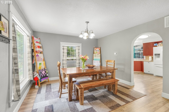 2472 Willamina Ave, Forest Grove, OR 97116 - dining room featuring arched walkways, light wood finished floors, a chandelier, and baseboards