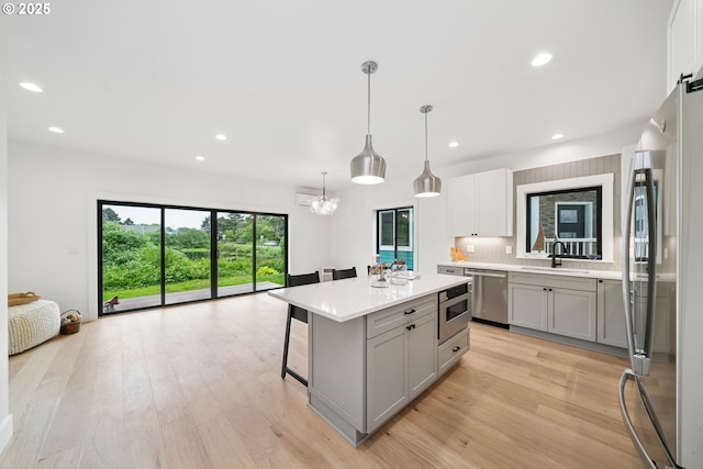 42 Washington St, Rockaway Beach, OR 97136 - kitchen with appliances with stainless steel finishes, gray cabinetry, light countertops, light wood-style flooring, and a kitchen bar