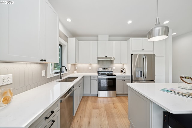 42 Washington St, Rockaway Beach, OR 97136 - kitchen featuring appliances with stainless steel finishes, light wood-type flooring, under cabinet range hood, backsplash, and recessed lighting