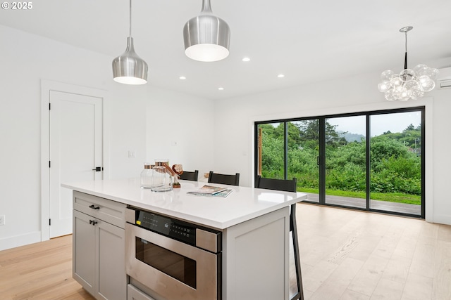42 Washington St, Rockaway Beach, OR 97136 - kitchen featuring stainless steel microwave, light countertops, light wood finished floors, decorative light fixtures, and recessed lighting