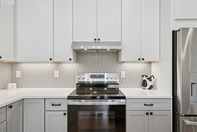 42 Washington St, Rockaway Beach, OR 97136 - kitchen featuring appliances with stainless steel finishes, under cabinet range hood, light countertops, and tasteful backsplash