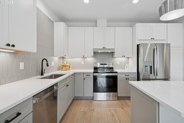 42 Washington St, Rockaway Beach, OR 97136 - kitchen featuring appliances with stainless steel finishes, under cabinet range hood, light wood-style floors, light countertops, and decorative backsplash