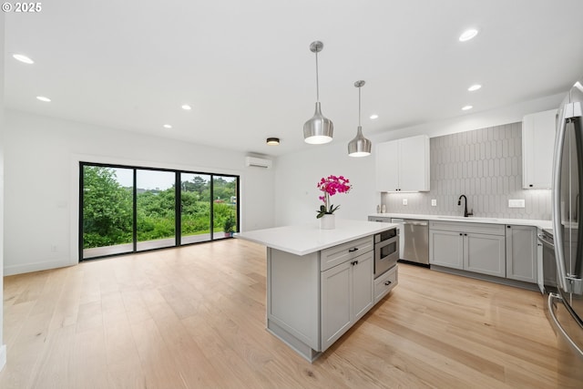 42 Washington St, Rockaway Beach, OR 97136 - kitchen with appliances with stainless steel finishes, gray cabinetry, light countertops, backsplash, and light wood-type flooring