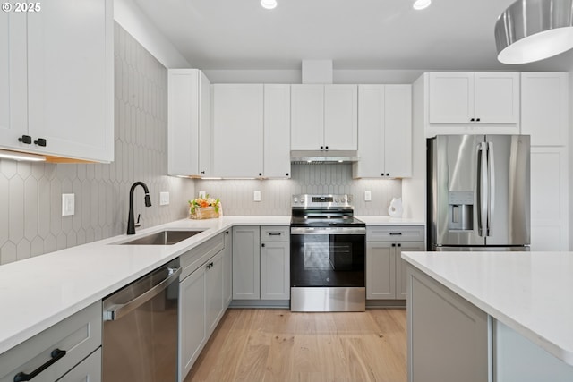 42 Washington St, Rockaway Beach, OR 97136 - kitchen featuring appliances with stainless steel finishes, under cabinet range hood, light wood-style floors, light countertops, and decorative backsplash