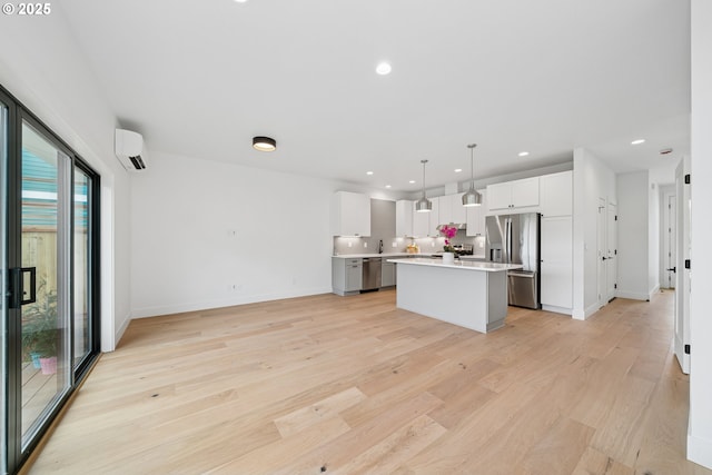 42 Washington St, Rockaway Beach, OR 97136 - kitchen featuring appliances with stainless steel finishes, a center island, light countertops, light wood-type flooring, and white cabinetry