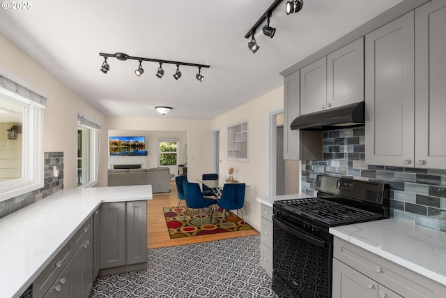 4545 SW Poplar Ln, Portland, OR 97225 - kitchen with black gas stove, under cabinet range hood, gray cabinets, open floor plan, and tasteful backsplash
