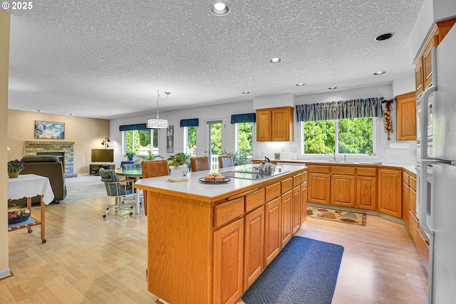 12459 SE Imperial Crest St, Happy Valley, OR 97086 - kitchen with black electric stovetop, light wood-style floors, a kitchen island, a textured ceiling, and a sink