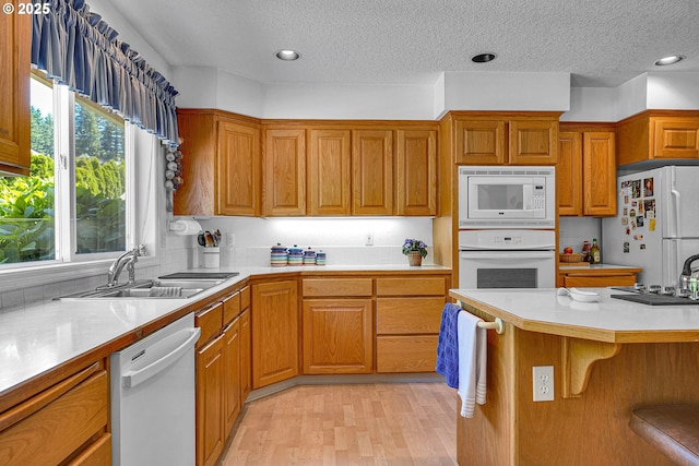 12459 SE Imperial Crest St, Happy Valley, OR 97086 - kitchen featuring white appliances, a sink, light countertops, brown cabinetry, and a textured ceiling