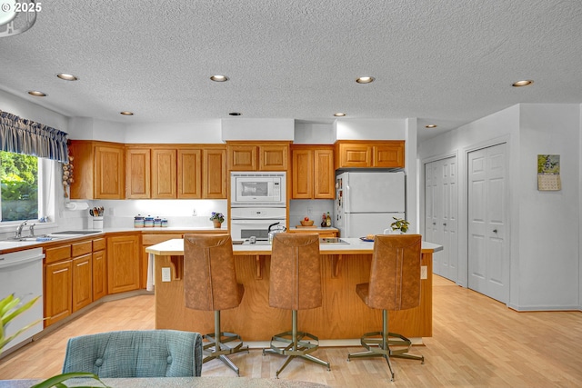 12459 SE Imperial Crest St, Happy Valley, OR 97086 - kitchen with white appliances, a sink, a center island, light countertops, and a textured ceiling