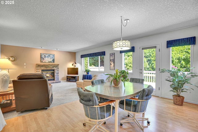 12459 SE Imperial Crest St, Happy Valley, OR 97086 - dining space featuring light wood-type flooring, a textured ceiling, and a fireplace