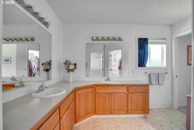 12459 SE Imperial Crest St, Happy Valley, OR 97086 - bathroom featuring double vanity, a textured ceiling, and a spacious closet