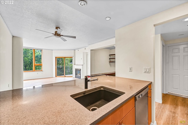 kitchen with sink, stainless steel dishwasher, ceiling fan, a textured ceiling, and light hardwood / wood-style flooring