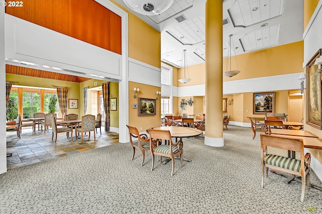 carpeted dining room with a towering ceiling