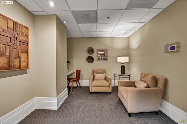 living area with a paneled ceiling and carpet