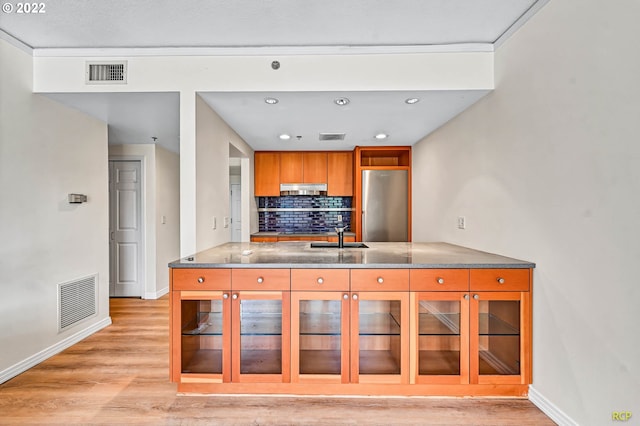 kitchen featuring backsplash, stainless steel fridge, sink, and light wood-type flooring