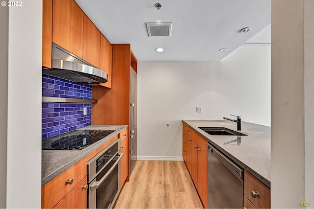 kitchen featuring extractor fan, tasteful backsplash, sink, light hardwood / wood-style floors, and stainless steel appliances