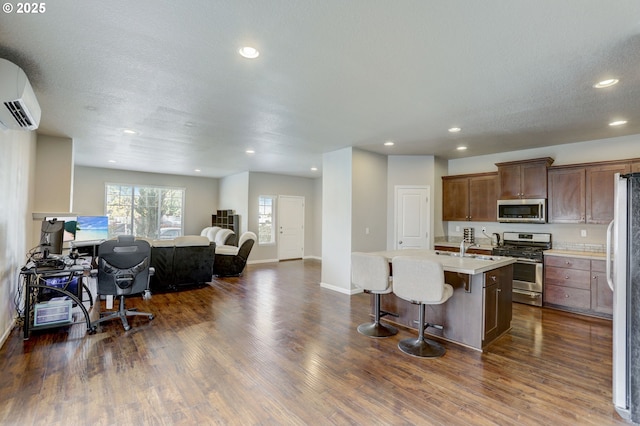 5141 SE Redberry Pl, Hillsboro, OR 97123 - kitchen featuring appliances with stainless steel finishes, open floor plan, a wall mounted air conditioner, a kitchen breakfast bar, and light countertops