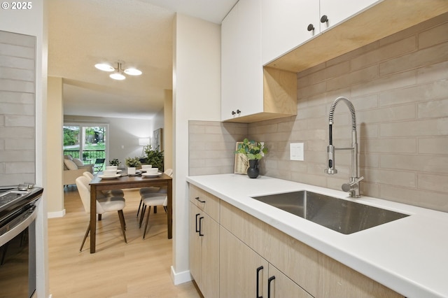 12620 NW Barnes Rd Unit 4, Portland, OR 97229 - kitchen with a sink, stainless steel electric range, light wood finished floors, backsplash, and light countertops