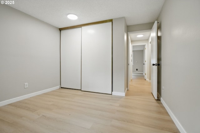 12620 NW Barnes Rd Unit 4, Portland, OR 97229 - unfurnished bedroom featuring light wood-type flooring, a closet, baseboards, and a textured ceiling