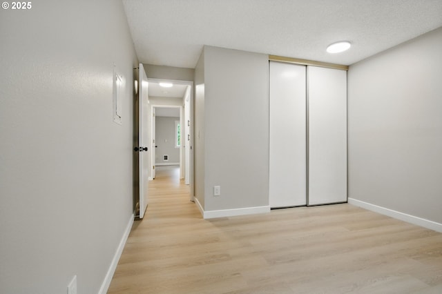12620 NW Barnes Rd Unit 4, Portland, OR 97229 - unfurnished bedroom featuring light wood-type flooring, baseboards, a closet, and a textured ceiling