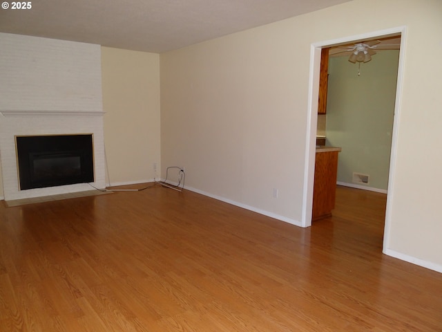 unfurnished living room with a fireplace, hardwood / wood-style floors, and ceiling fan