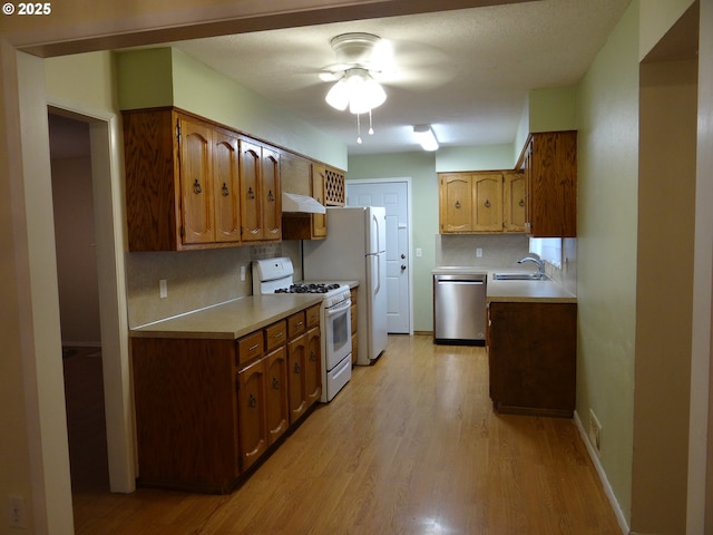 kitchen with light wood-type flooring, white appliances, sink, and tasteful backsplash