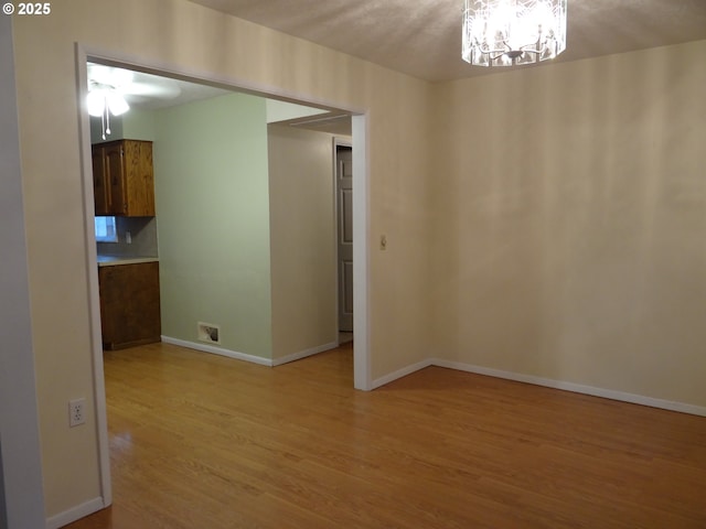 spare room featuring light hardwood / wood-style floors and an inviting chandelier