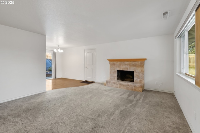 unfurnished living room with a fireplace, carpet floors, and a chandelier