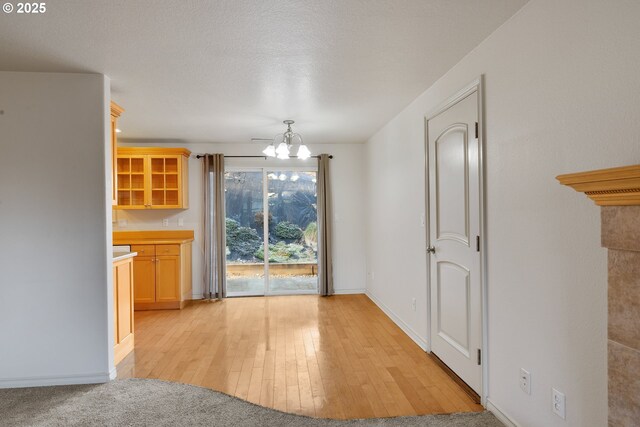 unfurnished dining area featuring an inviting chandelier, light hardwood / wood-style floors, and a textured ceiling