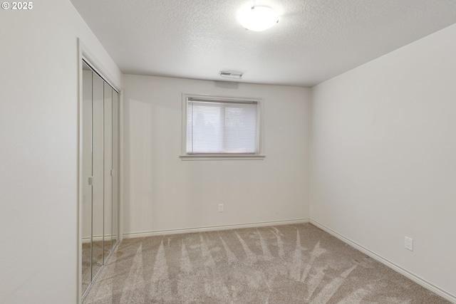 unfurnished bedroom with light colored carpet, a closet, and a textured ceiling