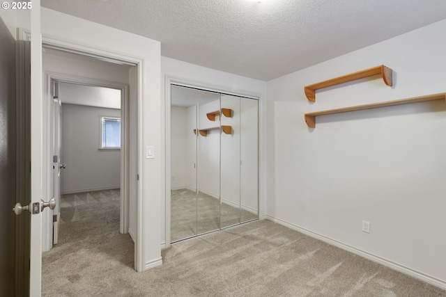 unfurnished bedroom with light colored carpet, a textured ceiling, and a closet