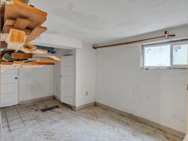 basement with light floors, a textured ceiling, and baseboards