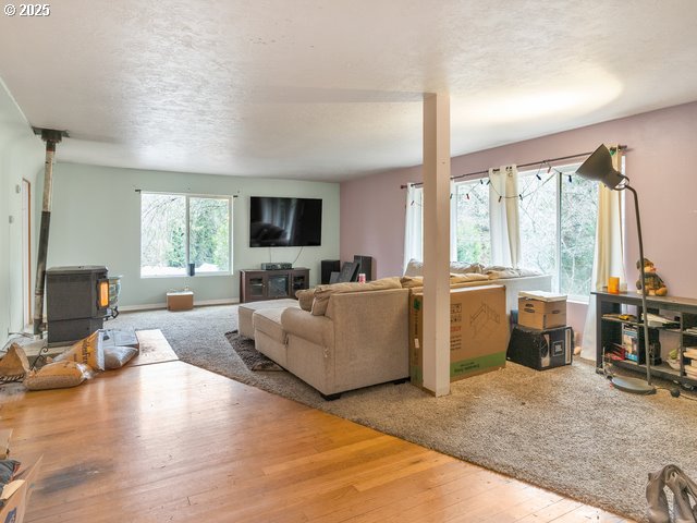 living room with a wood stove, wood finished floors, baseboards, and a textured ceiling