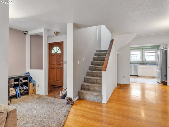 entrance foyer featuring light wood-style flooring, stairs, and baseboards