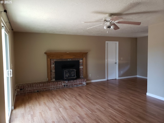 unfurnished living room with a wood stove, ceiling fan, a textured ceiling, and hardwood / wood-style flooring