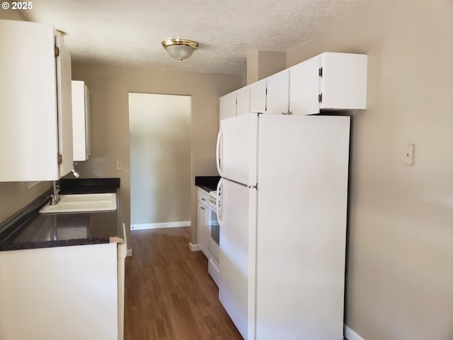 kitchen featuring a textured ceiling, sink, white refrigerator, dark hardwood / wood-style floors, and white cabinetry