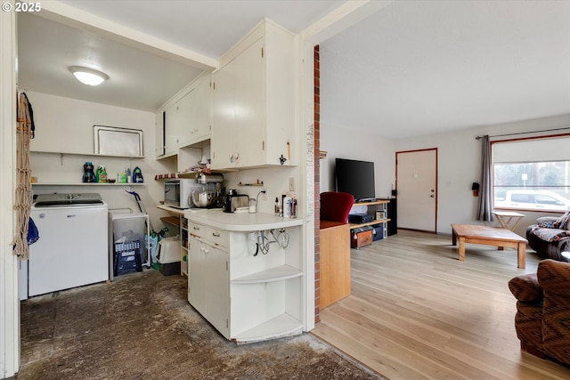 kitchen with white microwave, washer / dryer, open shelves, light countertops, and light wood-style floors