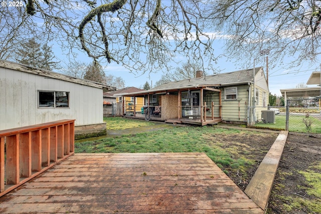 back of property featuring fence, a lawn, cooling unit, a deck, and a gate