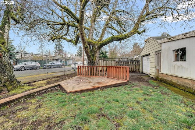 view of yard with a deck, a garage, and fence