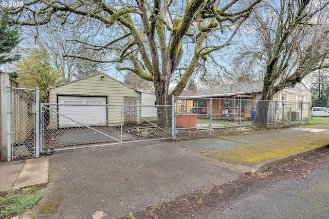 view of front of house featuring driveway, a gate, a fenced front yard, a detached garage, and an outdoor structure