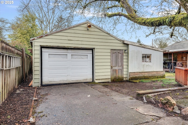 detached garage featuring aphalt driveway and fence