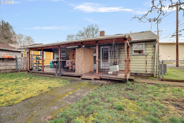 back of house featuring fence, a lawn, and a chimney