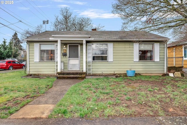 bungalow featuring a front lawn and a shingled roof