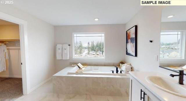 bathroom featuring tiled tub and vanity