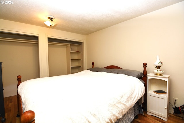 bedroom featuring dark wood-style floors, a textured ceiling, and multiple closets